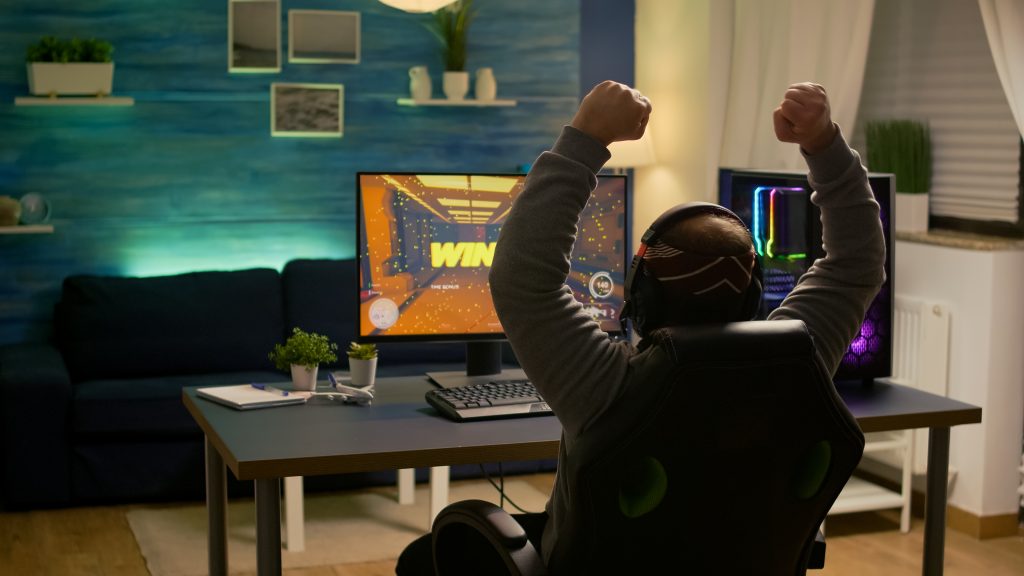 videogamer player raising hands after winning first person shooter competition wearing hradphones professional pro gamer playing online video games with new graphic PCI DSS для онлайн-ігор